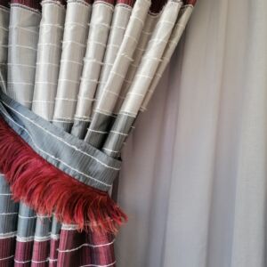 Κουρτίνα ραμμένη από ταφτά ριγέ σε αποχρώσεις μπορντό-γκρι και με ραφή τρίπιετο. Οι διαστάσεις είναι 1,10 χ 2,63 ύψος